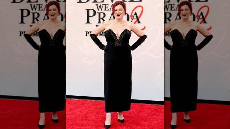 Rachel Bloom at the DWP2 premiere. She is a woman with fair skin, dyed red hair, and a fuller figure. She is wearing a strapless black dress with a plunging neckline, and sheer black opera gloves.
