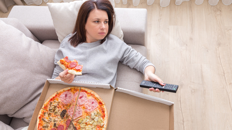 woman on couch eating pizza