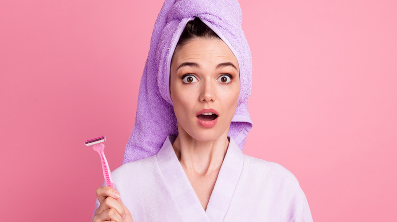 surprised woman wearing towel and holding razor