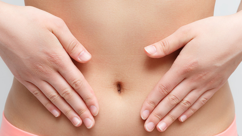 woman holds her hands to her stomach