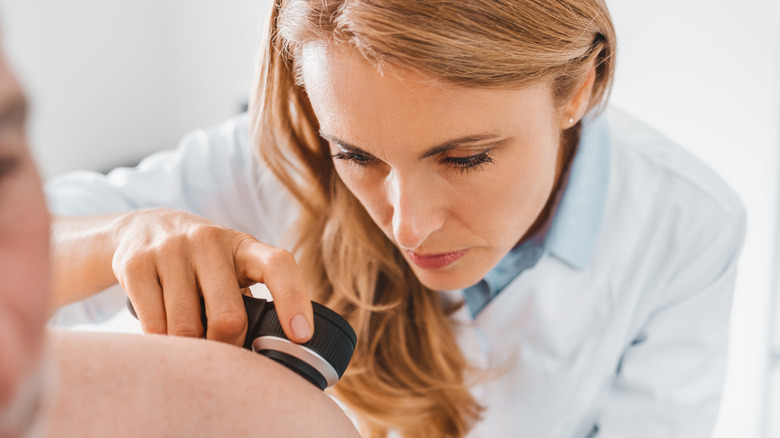 dermatologist examining back of patient