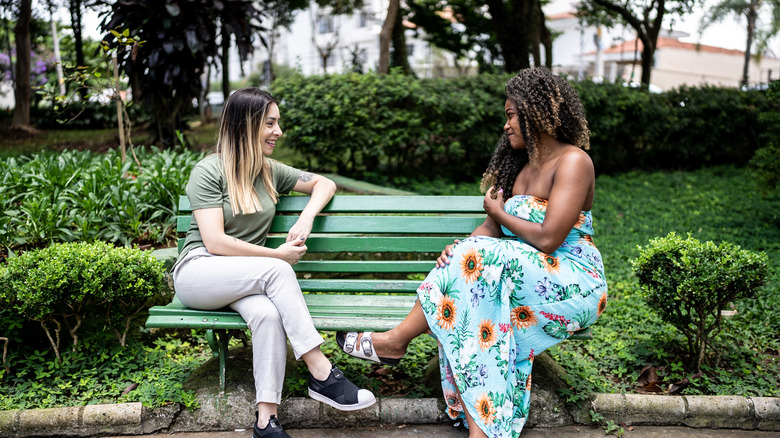 Two women talking on a bench in a park