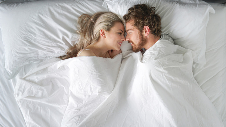 A couple in bed smiling at each other