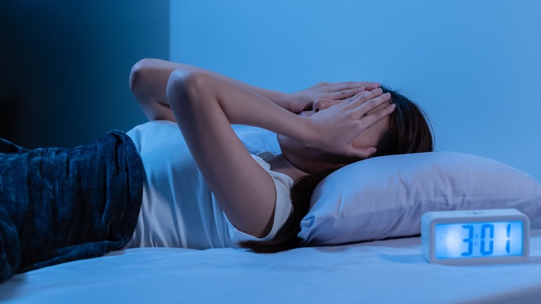 Person in bed with hands on face 