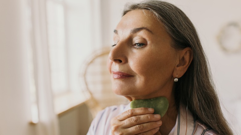 woman using gua sha on neck