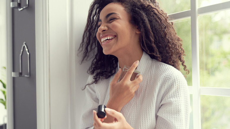 Woman spraying perfume on neck