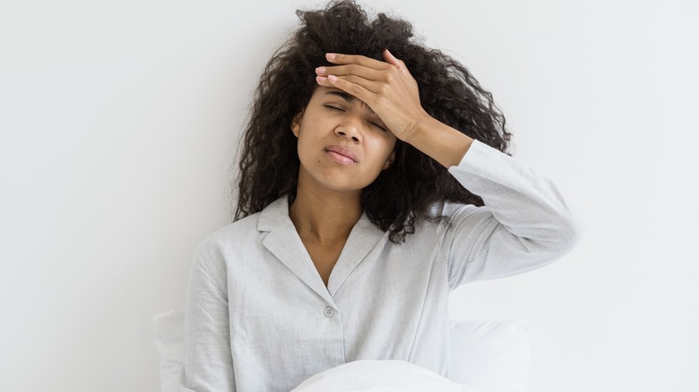 woman in bed touching forehead