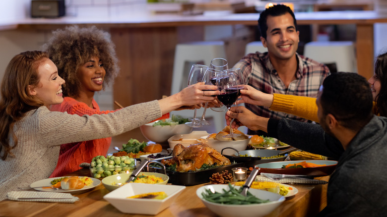 Group of friends toasting to dinner at holiday party 
