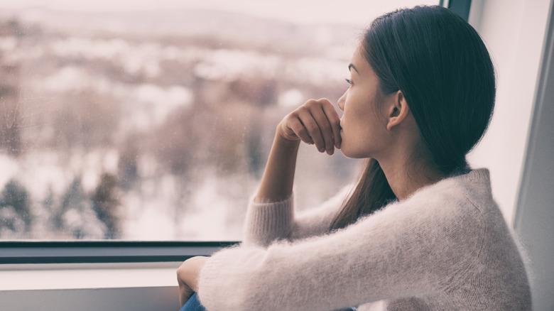Woman looking anxious in front of windowsill