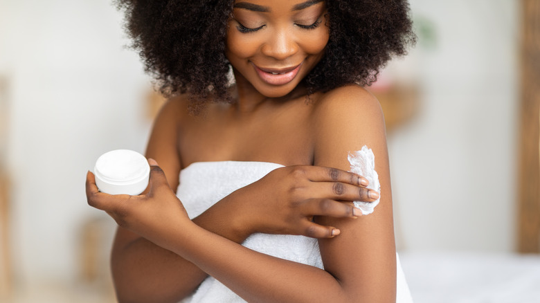 Woman applying body lotion