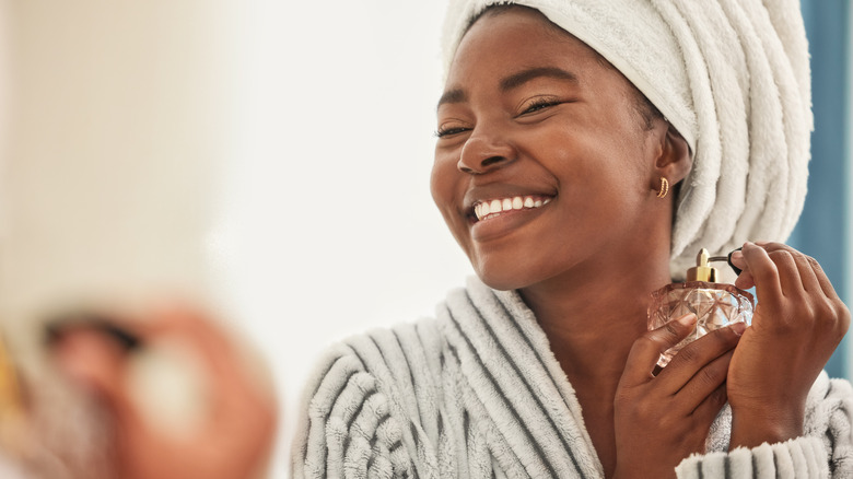 woman spraying perfume on body