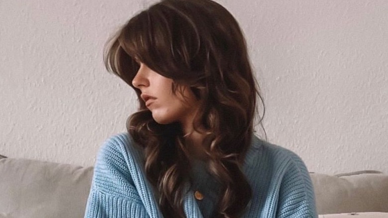 Woman with calligraphy haircut poses in bed