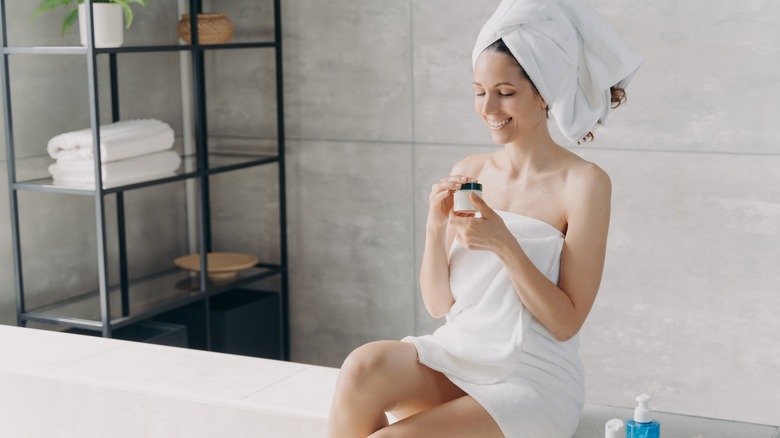 Woman sitting on bed wearing robe, towel on head