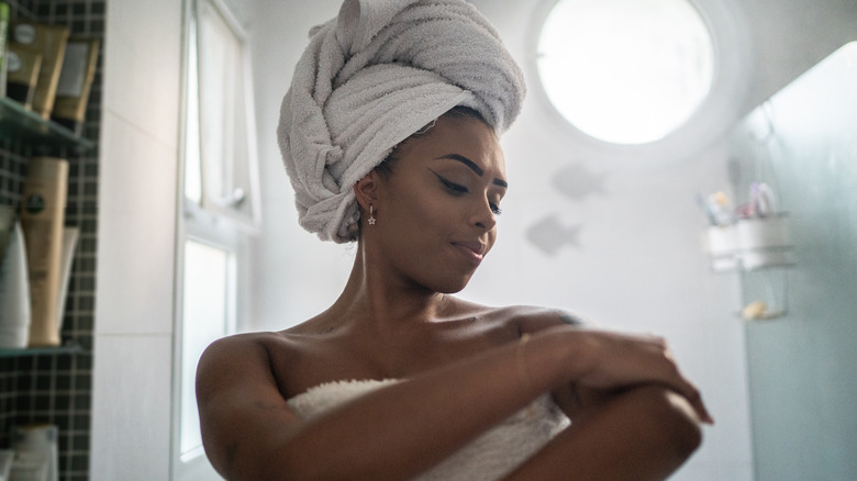 woman applying lotion in bathroom