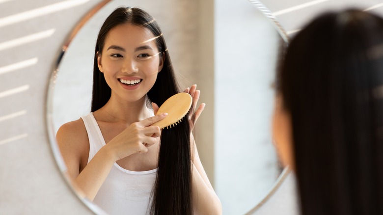 Woman brushing hair in mirror