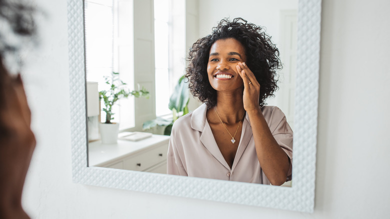 woman applying skincare in mirror