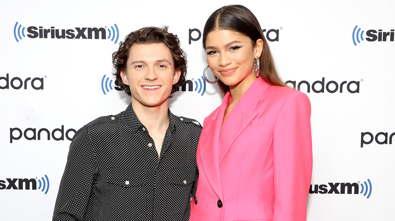 Zendaya and Tom Holland posing together, with Zendaya in a pink blazer