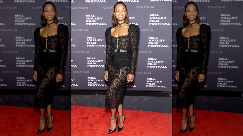 Zoe Saldaña wearing a black lace see-through dress at a red carpet event.