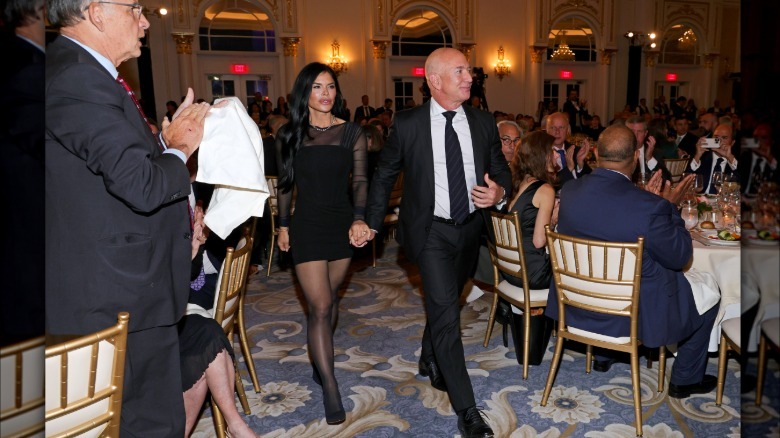 The full image of Lauren Sanchez and Jeff Bezos. Sanchez is wearing a black mini dress with sheer sleeves