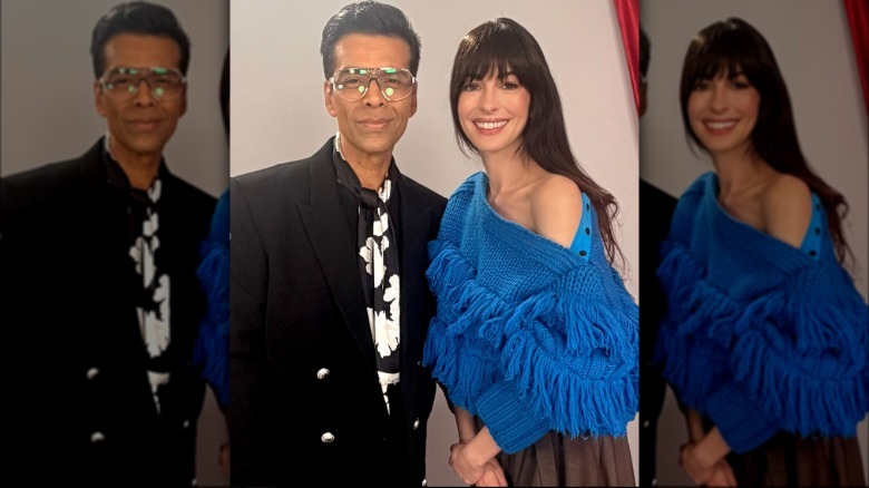 Anne Hathaway poses with journalist Karan Johar. She is wearing a bright blue off-the-shoulder sweater covered in blue fringe