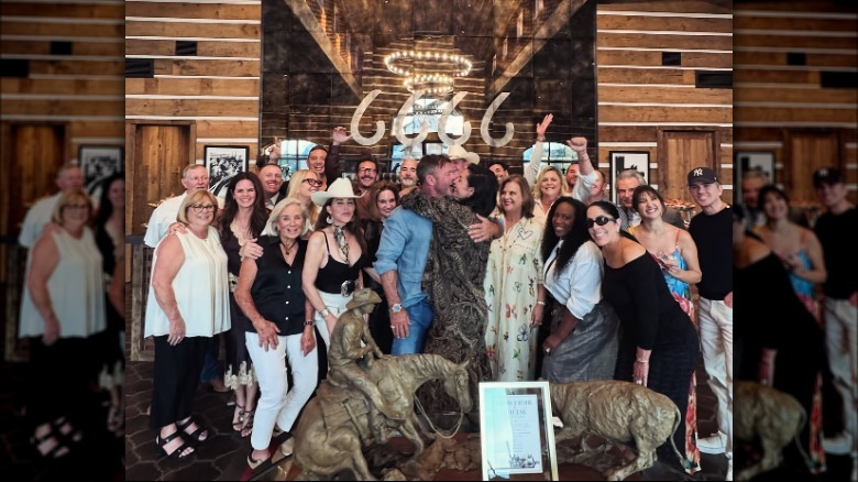 Nicole Sheridan and Taylor Sheridan kissing in front of their anniversary party guests.