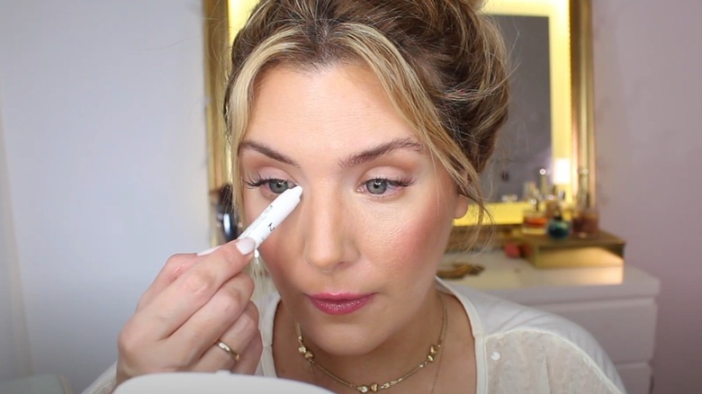 A woman using white eyeliner on her inner eye